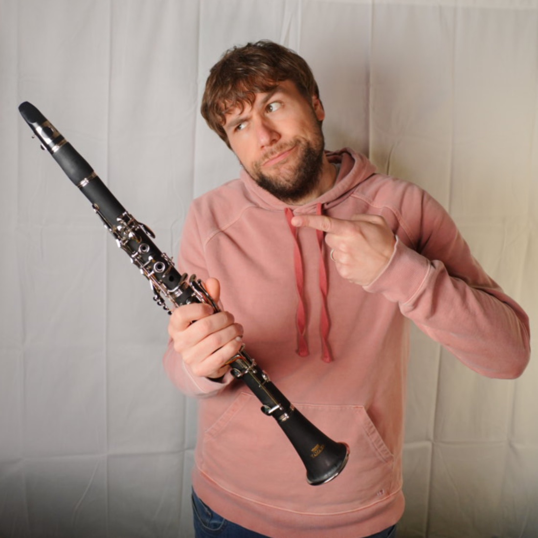 Chase Jamison holding a clarinet and pointing to it